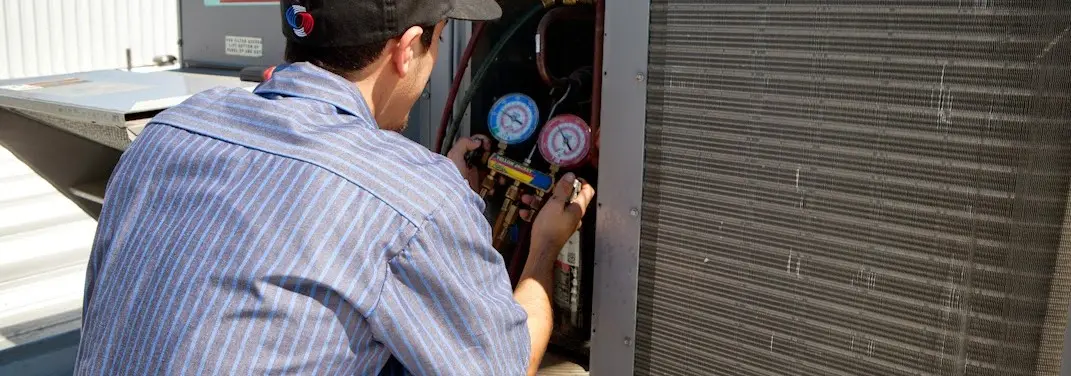 HVAC technician servicing a condenser unit in Wakefield